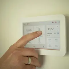 Ręka dotyka ekranu termostatu, ustawiając idealną temperaturę. Zastanawiasz się, jaką temperaturę ustawić na piecu gazowym kondensacyjnym?