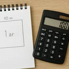 Notatnik z polem 10m x 10m (1 ar) i kalkulatorem pokazującym 100. Obliczenia ile rury na m2 ogrzewania podłogowego co 10 cm.