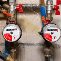 Dwa wodomierze z czerwonymi zaworami. Na jednym z nich widać informację o ciśnieniu P 1,0 Mpa, co może pomóc w ustaleniu, jakie ciśnienie w naczyniu przeponowym cwu.
