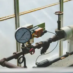 Manometr wskazuje prawidłowe ciśnienie w piecu gazowym. Rury i zawory są częścią instalacji.