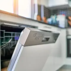 Otwarta zmywarka Sharp, panel sterowania z widocznym błędem F2. W tle kuchnia z płytkami i piekarnikiem.