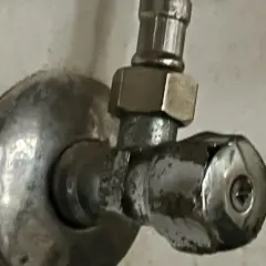 Metalowy zawór przy ścianie. Aby zamknąć wodę, należy go odkręcić w lewo.