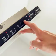 Dłoń naciska przycisk na panelu zmywarki Whirlpool, która wyświetla błąd F1.