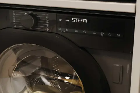 Nowoczesna pralka z panelem sterowania, na którym widnieje napis "STEAM". Czy pralka sama podgrzewa wodę? Tak, ta funkcja jest dostępna.