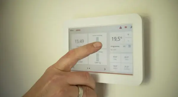 Ręka dotyka ekranu termostatu, ustawiając idealną temperaturę. Zastanawiasz się, jaką temperaturę ustawić na piecu gazowym kondensacyjnym?