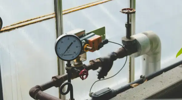Manometr wskazuje prawidłowe ciśnienie w piecu gazowym. Rury i zawory są częścią instalacji.