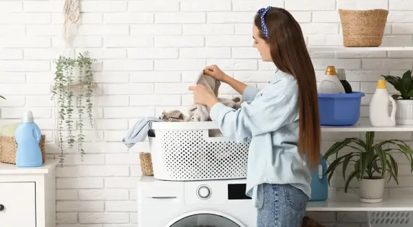 Dziewczyna sortuje pranie, obawiając się, że pralka brudzi ubrania na szaro.