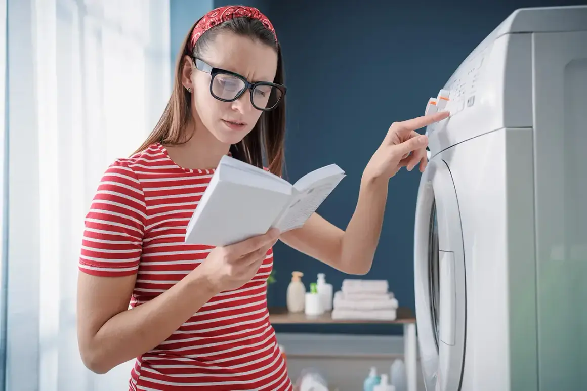 Kobieta z okularami i czerwoną opaską na włosach czyta instrukcję, próbując rozwiązać problem z pralką, być może błąd E10.