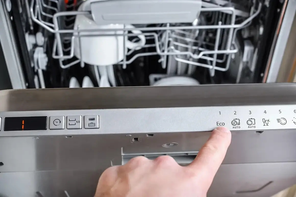 Palec wskazuje przycisk "Eco" na panelu zmywarki Gorenje, która wyświetla błąd F12.