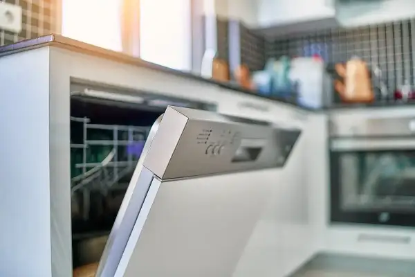 Otwarta zmywarka Sharp, panel sterowania z widocznym błędem F2. W tle kuchnia z płytkami i piekarnikiem.