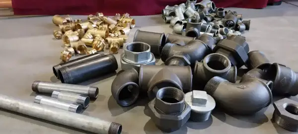 Różnorodne złączki i rury stalowe, mosiężne oraz ocynkowane. Wiele z nich ma gwinty, co ułatwia połączenie rury stalowej z plastikową za pomocą odpowiednich adapterów.