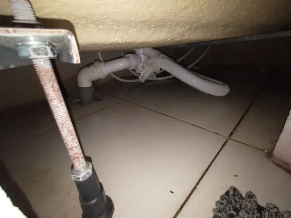 Podczas wymiany syfonu w wannie zabudowanej, widać instalację hydrauliczną pod wanną i odpływ.